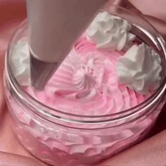 someone is mixing pink icing in a glass jar