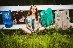 a woman sitting in the grass next to some shirts