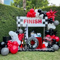 a table topped with balloons and black and white decor in front of a fenced area