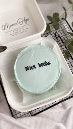 a cake in a white box with writing on it and some green leaves next to it