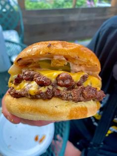 a person holding up a sandwich with meat and cheese