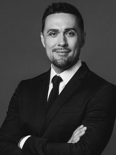 a black and white photo of a man in a suit with his arms crossed looking at the camera