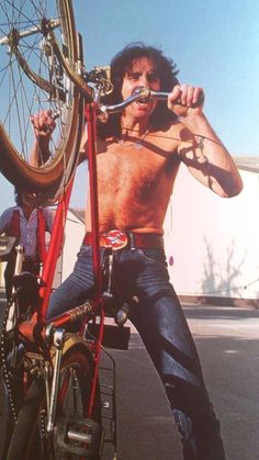 a shirtless man sitting on top of a bike holding onto the handlebars