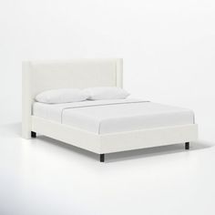 a bed with white sheets and pillows on it