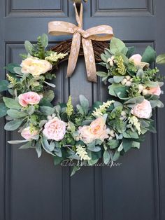 a wreath with flowers and greenery hanging on the front door for an elegant look