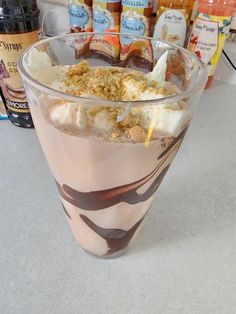 a drink with ice cream and toppings in a glass on a table next to bottles