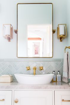 a bathroom sink sitting under a mirror next to a white counter topped with gold faucets