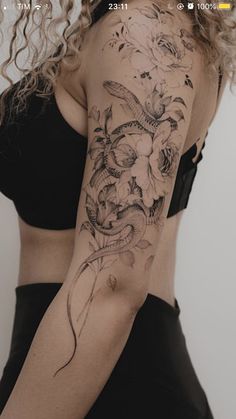 a woman with a snake and flowers tattoo on her arm is looking at the camera