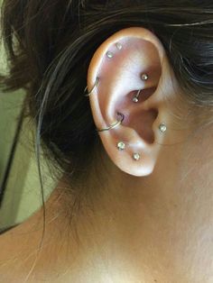 a woman's ear with three piercings attached to the back of her ear