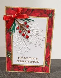 a christmas card with holly and red berries on it, the words season's greetings written in gold foil