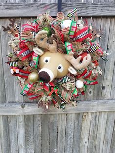 a christmas wreath hanging on the side of a wooden fence with deer head and ornaments