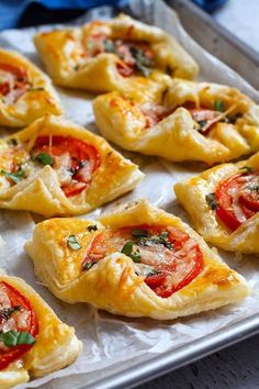 small pizzas with tomatoes and cheese on a baking sheet