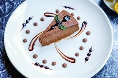 a piece of cake on a white plate with chocolate sauce and mint sprigs