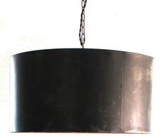 a black lamp hanging from a chain on a white wall with a light fixture in the middle