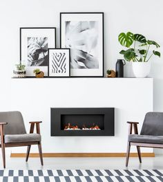 two chairs and a fire place in a room with pictures on the wall behind them