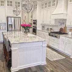 a large kitchen with white cabinets and marble counter tops