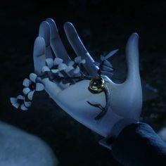 a hand that has some kind of ring in it's palm with flowers on it