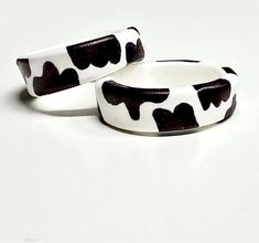 two black and white cow print bangles on top of each other with hearts painted on them