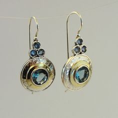 A wonderful new design hanging earrings. Elegant NEW pair of earrings in round shape from my collection with 8mm round Blue Topaz inlaid in 15mm diameter 925 solid silver, framed with 2mm wide 9K polished solid yellow gold. Also, these hanging earrings has three tiny Blue Topaz CZ that give them charming look. These are great new design pair of earrings, don't miss! Drop/Dangle earrings, fits any occasion. Will upgrade any look and show your unique fashion style. Perfect Gift for you and your lo Elegant Blue Topaz Earrings With Ear Wire, Nickel Free Blue Topaz Drop Earrings, Fine Jewelry Blue Topaz Round Earrings, Elegant Nickel-free Blue Topaz Earrings, Elegant Blue Topaz Nickel-free Earrings, Blue Topaz Round Pierced Earrings, Hallmarked Round Blue Topaz Earrings, Pierced Blue Topaz Round Earrings, Pierced Round Blue Topaz Earrings