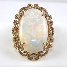 This A Fancy Fine Huge Oval Cut Fire Opal Solitaire Ring W/Diamond Filigree Halo. It Is Made Of 100% Natural 14kt Rose Gold And Is In Brand New Condition. It Has A Ctw Of 12.46ct (.88 Diamond/11.58 Opal) And Weighs 10.4 Grams. The Fancy Diamonds Have A Clarity Of Si1 And G Color. This Beautiful Custom Piece Has An Excellent Oval Cut Opal Stone, Surrounded By A Diamond Filigree Halo With Accents. Luxury Opal Ring With 17 Jewels For Anniversary, Luxury 14k Gold Opal Ring, Luxury White Gold Opal Ring, Luxury White Oval Opal Ring, Luxury White Opal Ring, Luxury White Gold Opal Ring For Formal Occasions, Luxury Opal Ring With Diamond And Round Cut, Luxury Diamond Opal Ring With Round Cut, Luxury Opal Ring Accented By Diamonds