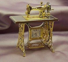 an antique sewing machine is sitting on a table with a clock in front of it