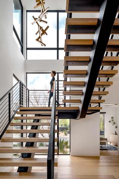 a woman standing on the stairs in a modern house with wood and metal railings