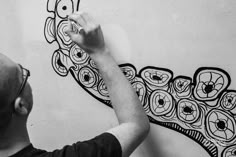 a man is drawing on the wall with black and white colors in front of him