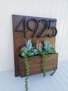 a wooden house number sign with succulents in it