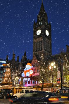 a large clock tower towering over a city filled with traffic under a snow covered sky