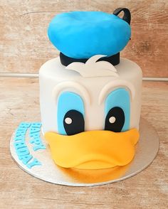 a blue and white cake with a ducky face on it's top is sitting on a wooden table