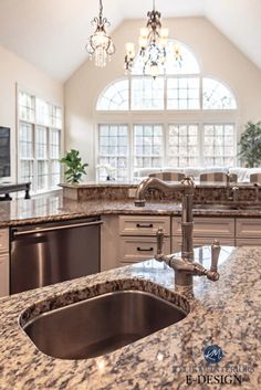 a large kitchen with granite counter tops and stainless steel appliances in front of an arched window