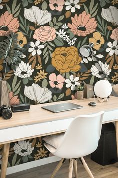 a desk with a laptop on top of it in front of a flower wallpaper