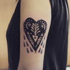 a black and white heart tattoo on the right arm with rain drops coming out of it