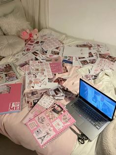 an open laptop computer sitting on top of a bed covered in pink and white stickers