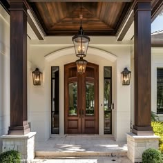 the front entrance to a house with two large doors and three lights on each side