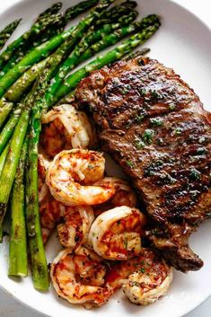 steak, shrimp and asparagus on a white plate