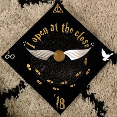 a black and gold graduation cap with white wings