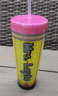 a pink and yellow cup sitting on top of a wooden table