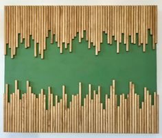 an art piece made out of bamboo sticks on a green surface with white walls and flooring