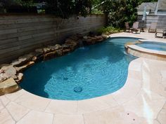 a small pool surrounded by rocks in a backyard