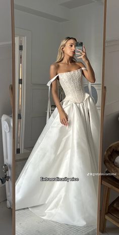 a woman in a white dress taking a selfie with her cell phone while standing in front of a mirror