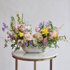 a white vase filled with lots of flowers sitting on top of a marble topped table