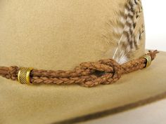 Dazzle in Distinctive Fashion: Elevate your style with our exquisite Middle-Brown Woven Hatband! Each piece is meticulously handcrafted from genuine calf leather strips, intricately woven into a timeless braided pattern. Two gleaming gold-tone metal beads or cylinders elegantly secure this band in place, adding a touch of luxury to your headwear. Adjustable Elegance: The beauty of this hatband lies in its versatility and personalization. The back of the band features an adjustable strap, ensurin Leather Hat Bands, Cowboy Hat Band, Custom Cowboy Hats, Cowboy Hat Bands, Braided Pattern, Hat Bands, Leather Hat, Leather Crafts, Western Hats