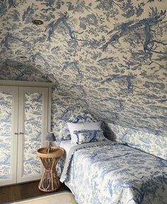 a bedroom with blue and white wallpaper in the corner next to a small bed