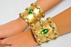 two gold bracelets with green stones on them