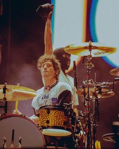 a man with his arm in the air while playing drums