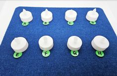 several white plastic knobs with green letters on a blue mat, and one has the letter e