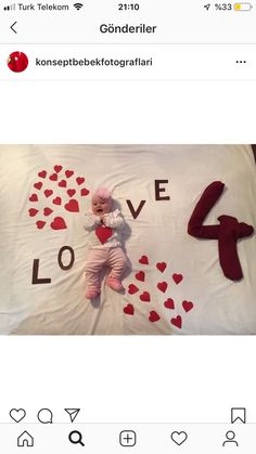 a baby laying on top of a bed with hearts and the word love spelled in red