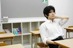 a person sitting at a desk with headphones in front of him and bookshelves behind them