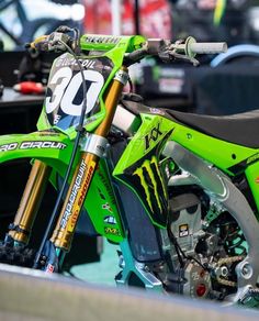 a green dirt bike parked next to a truck